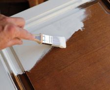 Person painting over wooden kitchen cabinet door