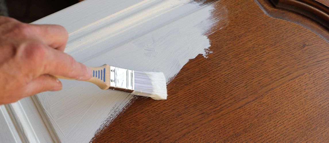 Person painting over wooden kitchen cabinet door