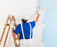 person using a paint roller painting an exterior wall