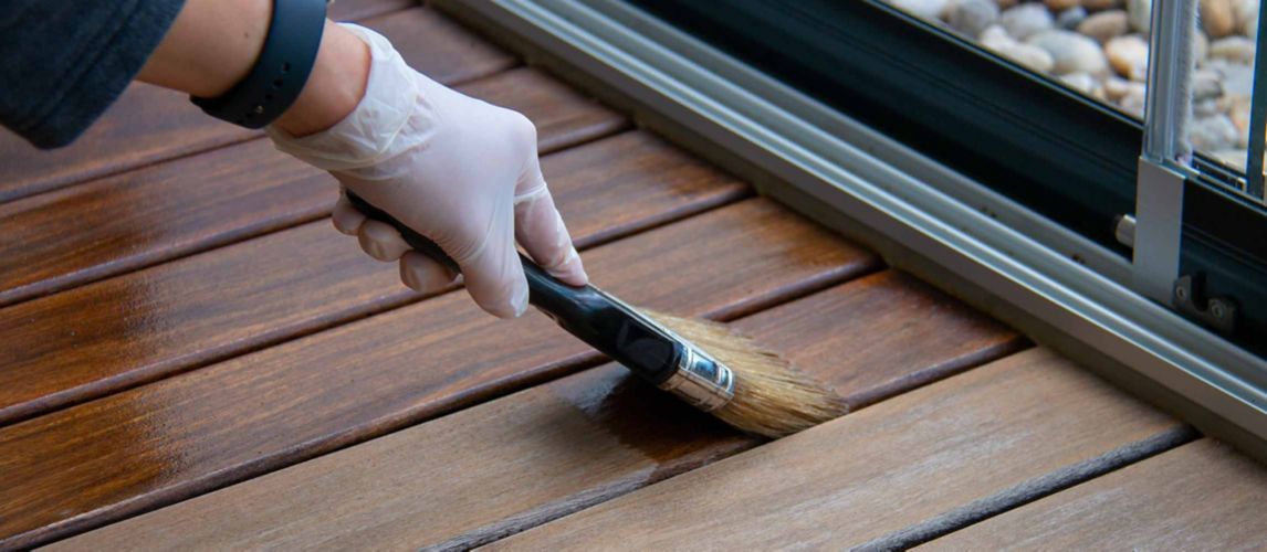 person holding paintbrush painting over varnished wood