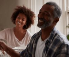 Man and woman smiling as they paint a wall together