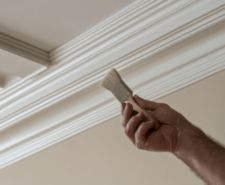 Person touching up paint on trim using a small paint brush with precision.
