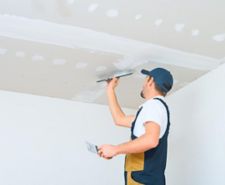 A man applies skims plaster on a ceiling