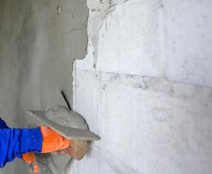 Person plastering a brickwork wall