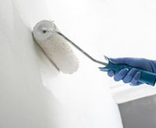 Man’s hand in work gloves applying PVA on the wall to clean before plastering