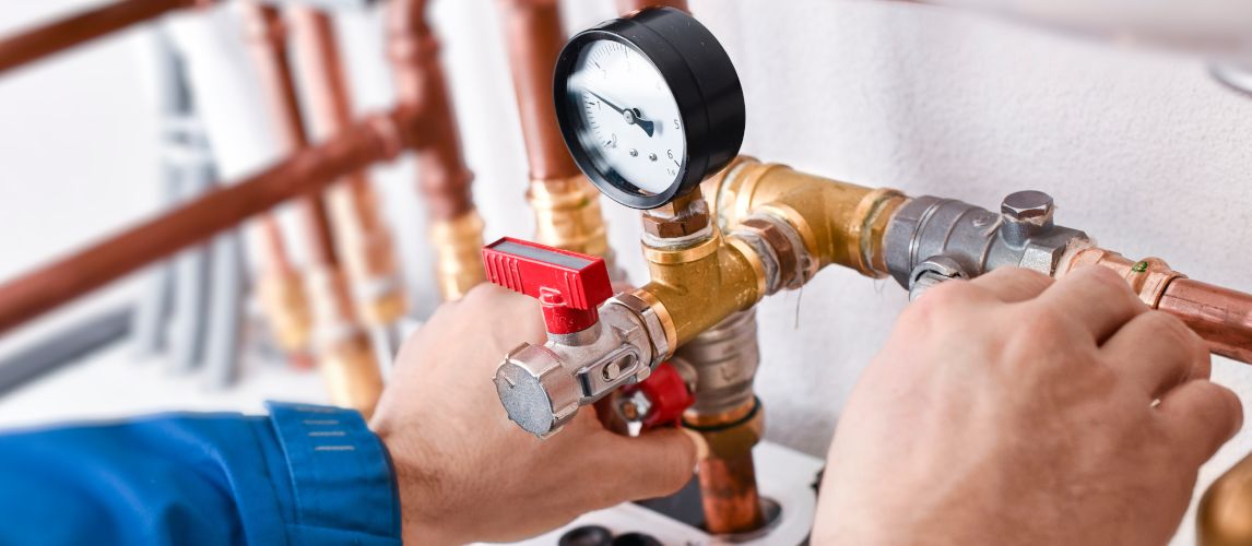 A technician adjusting the pressure valve on a boiler system.
