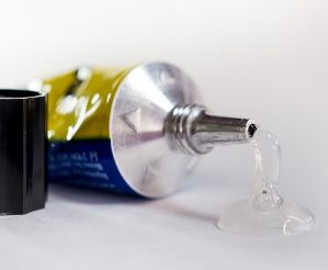 Tube of glue left on its side leaking on a table