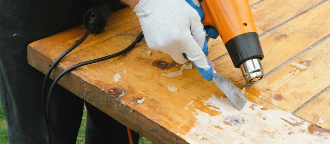person removing varnish from wood