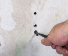 male hand handing pliers, removing a wall plug from a wall
