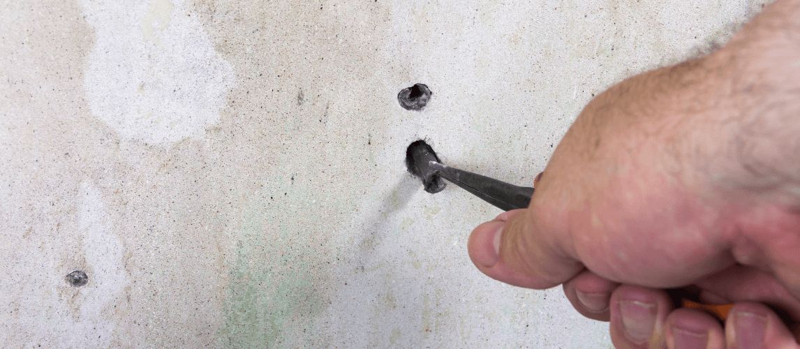 male hand handing pliers, removing a wall plug from a wall