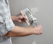 Man filling a hole in a wall with multipurpose filler