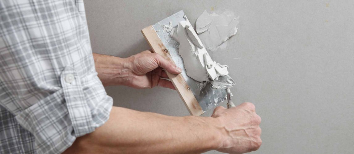 Man filling a hole in a wall with multipurpose filler