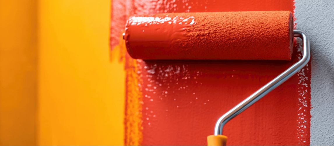 paint roller covered in red paint on wall