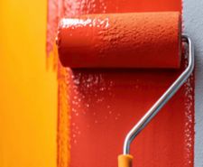 paint roller with red paint on wall