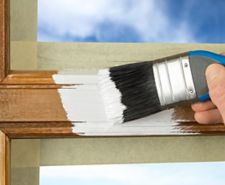 close up of a paint brush painting white paint onto a wooden window frame