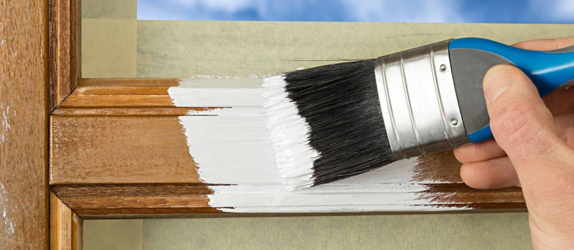 close up of a paint brush painting white paint onto a wooden window frame