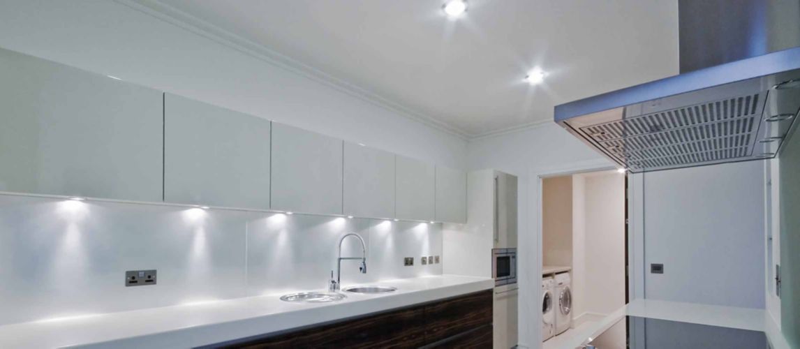 A kitchen with two downlights on the ceiling and six installed under cabinets