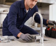 Handyman fixing a dripping tap in a kitchen