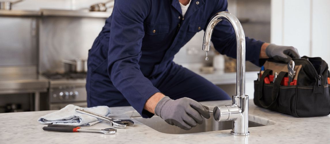 Handyman fixing a dripping tap in a kitchen