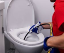 man using pressure washer system to unblock toilet