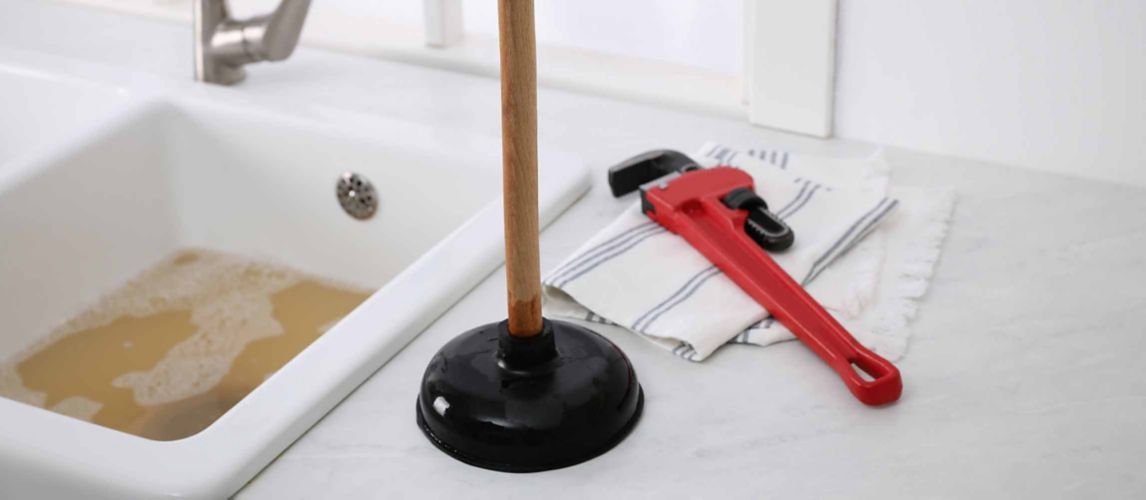 bathroom sink with plunger and wrench next to it
