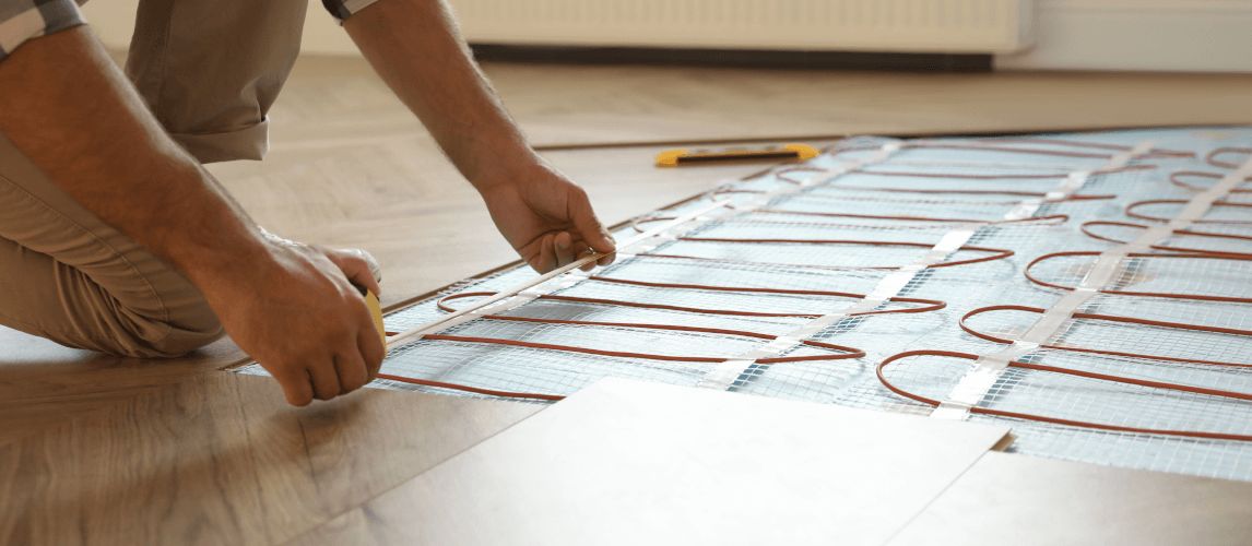 Professional worker installing electric underfloor heating system indoors
