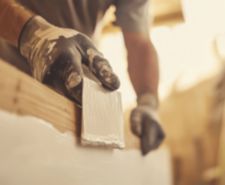 Construction worker applying a coat of primer to wooden surfaces before painting. Featuring surface preparation and painting
