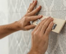 person measuring wallpaper on wall