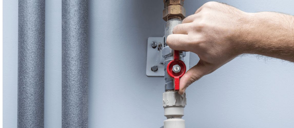 Plumber turning under the sink water supply shut-off valve.