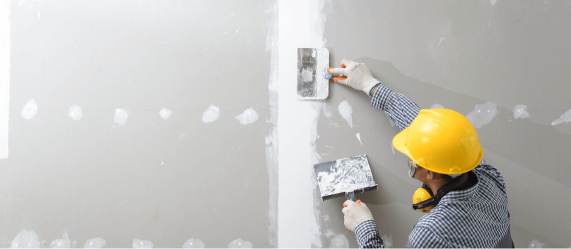 Worker applying plaster to a drywall joint.