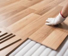 gloved hand laying laminate flooring