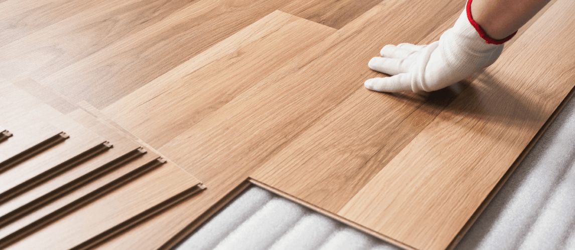 gloved hand laying laminate boards